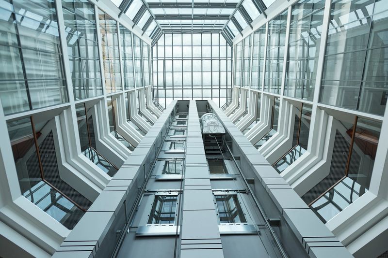 Below view of design of contemporary business center interior surrounded by walls and windows and moving elevator