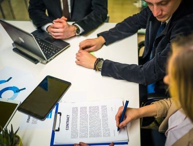 People reviewing and signing a contract at a business meeting.