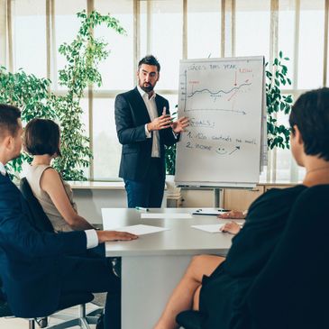 Businessman presenting sales goals to colleagues in a meeting room.