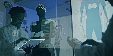 Scientist interacting with a digital tablet next to a humanoid robot and schematic display.