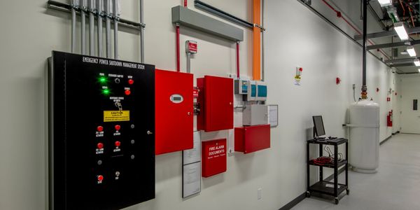 Industrial emergency power shutdown and fire alarm control panels on a clean wall.