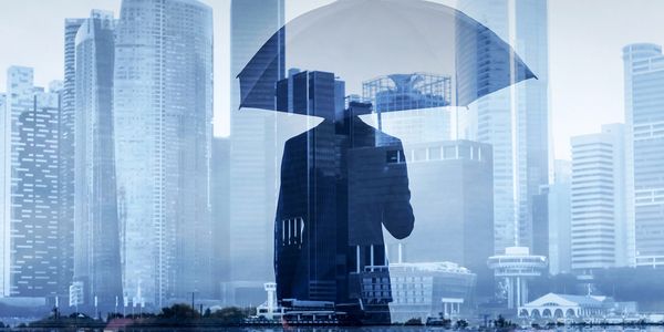 Silhouette of a person with umbrella against cityscape.