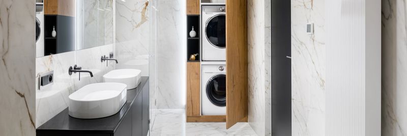 Panorama of elegant bathroom with washing machine and clothes dryer in wooden closet