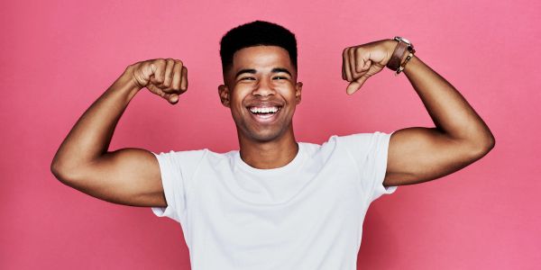 Young man flexing his muscles and smiling.