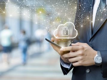 Businessman using smartphone with cloud security icon overlay.