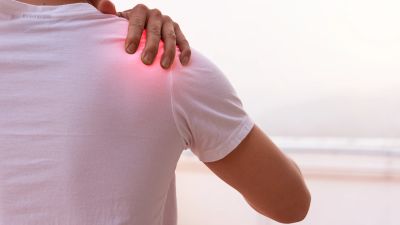 Person holding painful shoulder with red highlight.