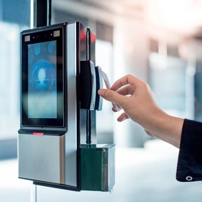 Hand holding access card near biometric scanner for entry.
