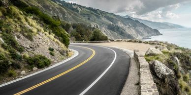 Curvy coastal road with ocean views and rocky cliffs.