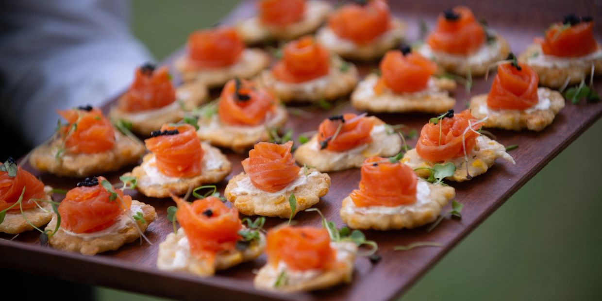 Appetizers with smoked salmon on crackers.