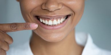 Close-up of a smiling person pointing at their healthy gums