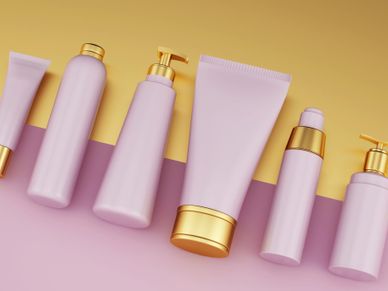 Elegant pink and gold cosmetic bottles and tubes arranged on a pastel background.
