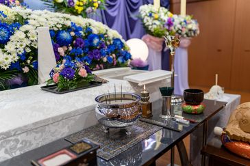 A ceremonial altar with incense and floral arrangements in a traditional setting.