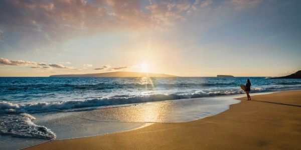Person standing on beach at sunset.