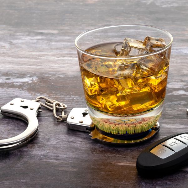a glass of whiskey next to car keys on top of handcuffs