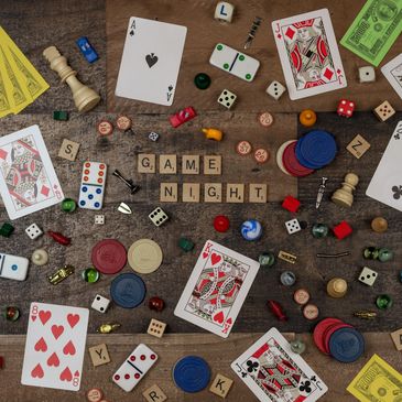 Board game pieces and cards spell out 'Game Night' on a wooden table.