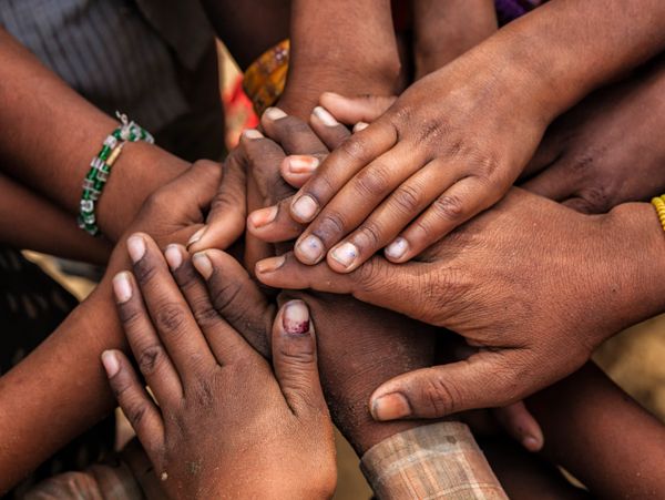 Multiple hands stacked together symbolizing unity and support.