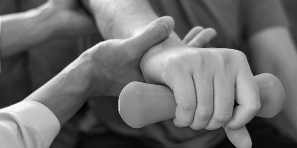 Hand gripping and restraining another hand holding a dumbbell.