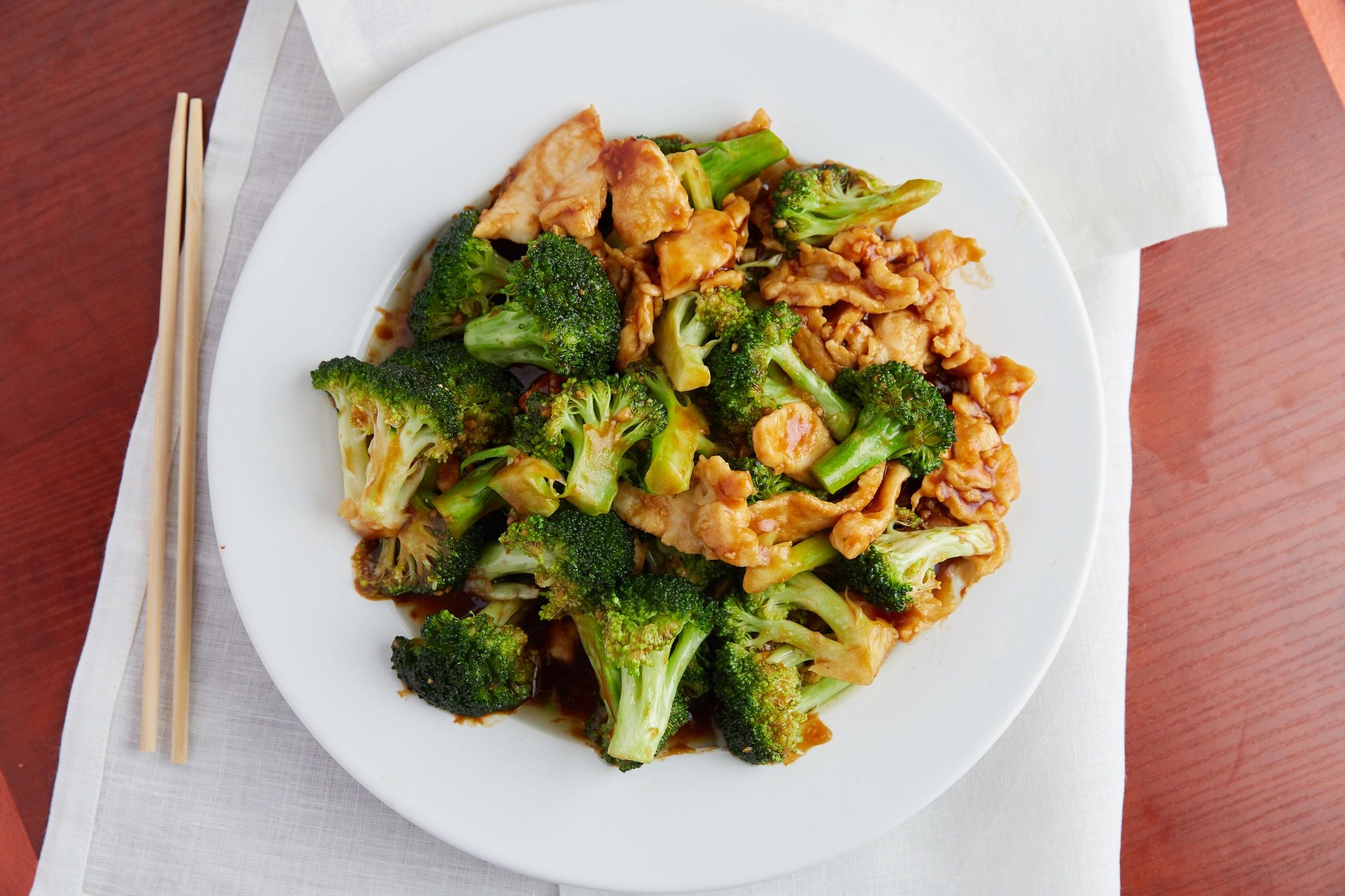 Plate of chicken and broccoli stir-fry with chopsticks.