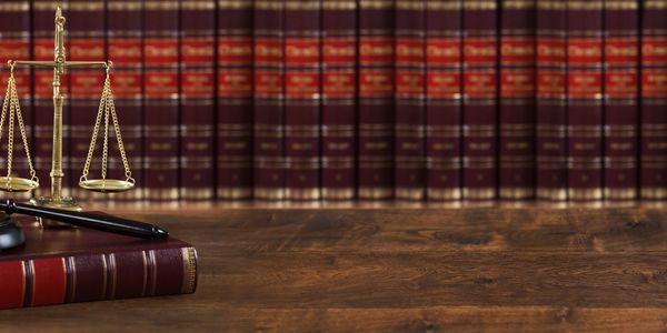 Scales of justice and law books on a desk.