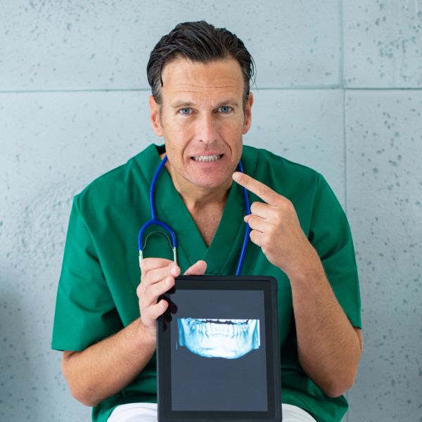 Doctor señala su boca mostrando una radiografía dental.