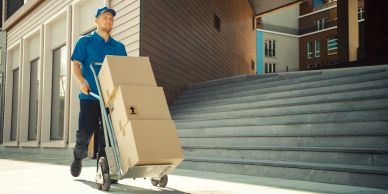 Delivery man carrying boxes on a hand truck.