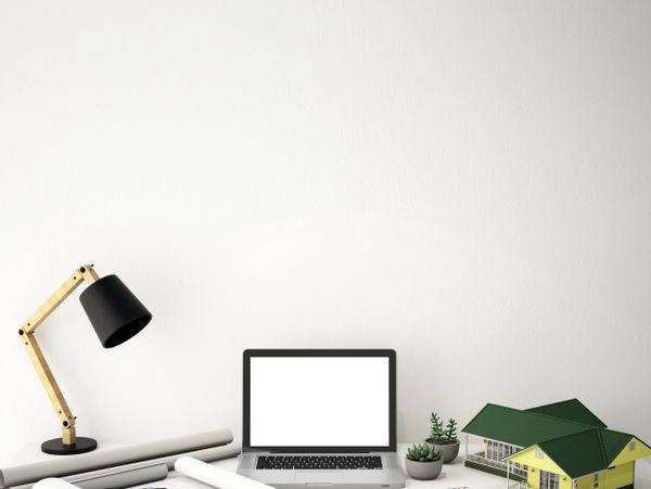 Modern workspace with architectural tools, laptop, and a house model on a clean desk.