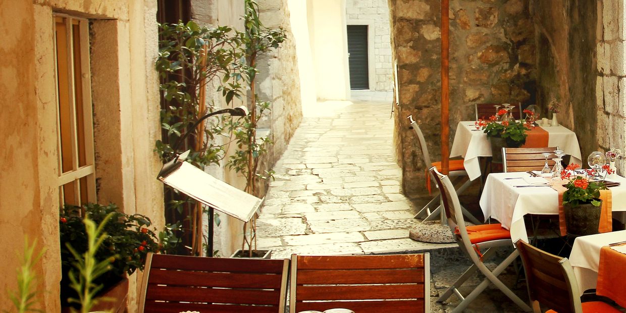 Cozy outdoor restaurant seating with stone walls and tiled floor in a narrow alley.