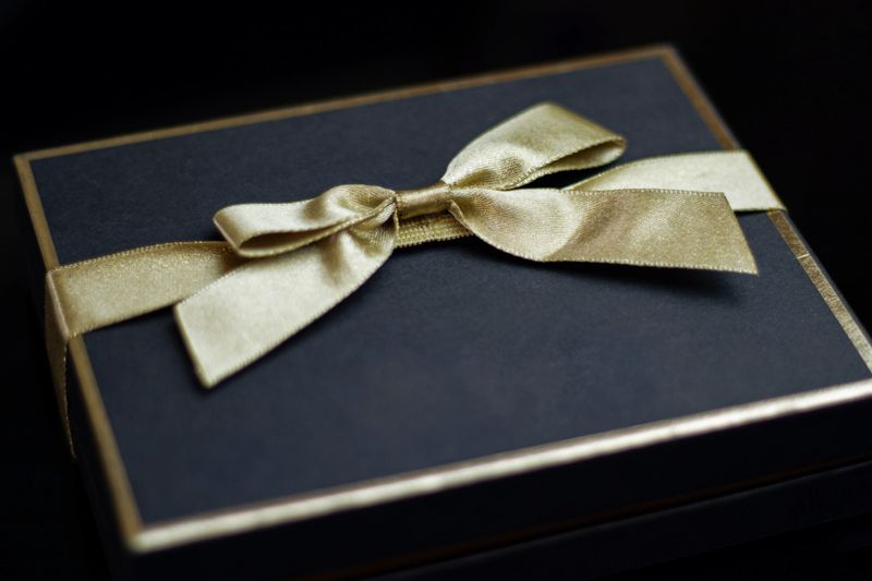 Close-up Dark Blue Gift Box and Gold Ribbon On Black Background. Horizontal composition with copy space.