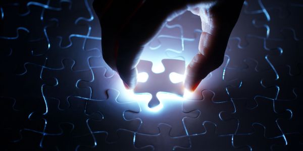 Hand placing the final glowing puzzle piece.