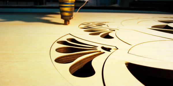 Laser cutting intricate patterns on wooden sheet.