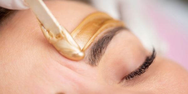 Wax strip being applied to a person's eyebrow for hair removal.