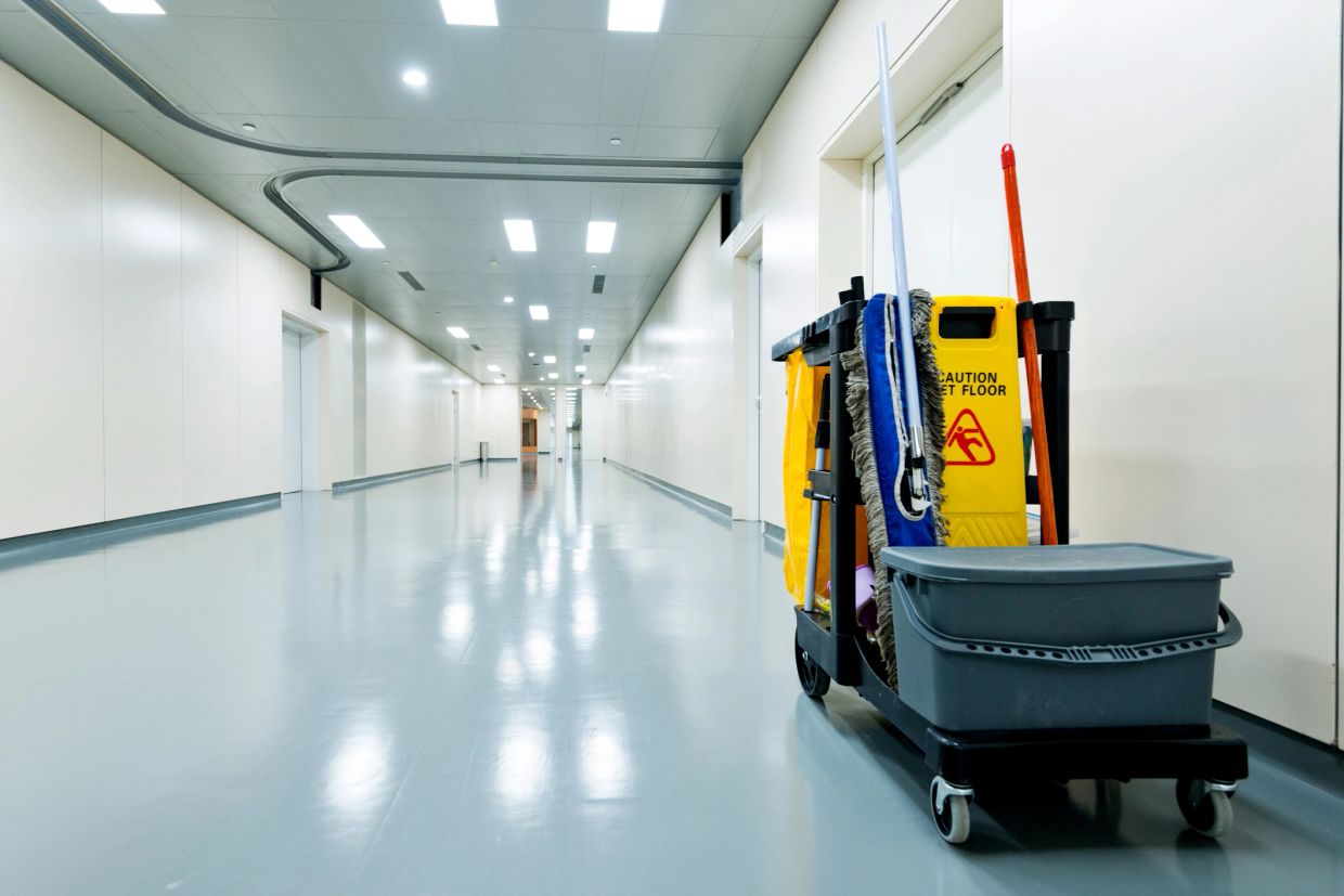 Cleaning cart in an empty, brightly lit hallway.