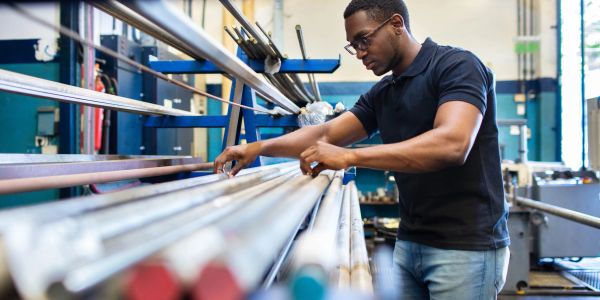 Man working with metal rods in a workshop.