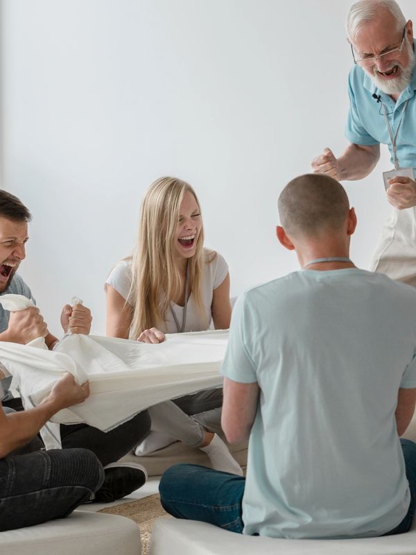 A group of people enthusiastically playing a team-building game indoors.