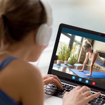 Persona sigue una clase de yoga en línea desde su laptop.
