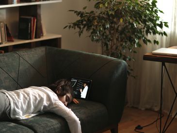 Person sleeping on a couch with a tablet.