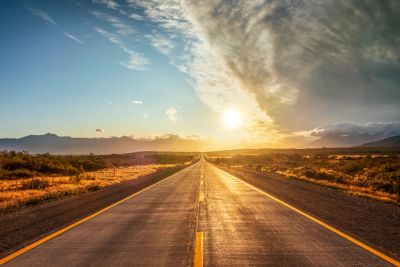 Sunset over an open road in a desert landscape.