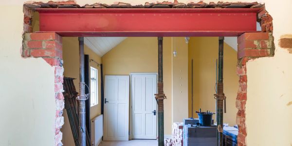 Wall opening under construction with support beams and bricks.