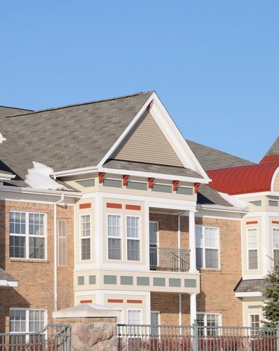 Modern brick townhouse with white and red trim under clear blue sky.