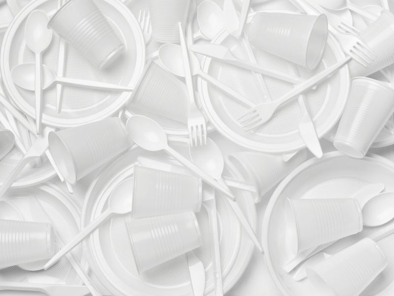 close up of plastic cutlery spoon, fork, knife, plate and cup on white background