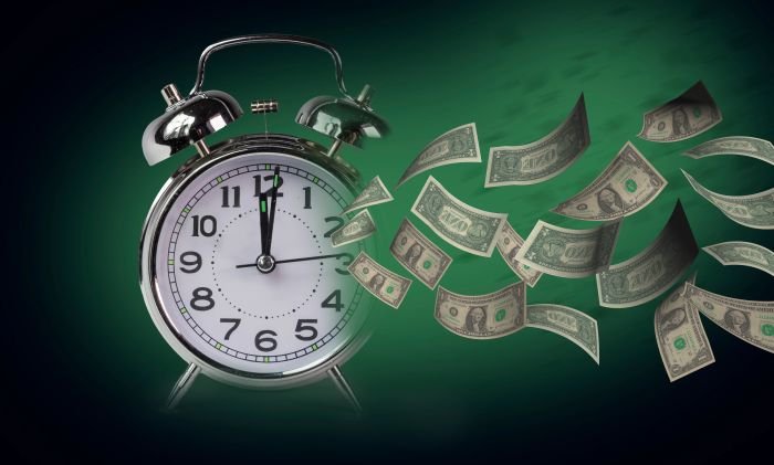 Alarm clock with flying dollar bills symbolizing time is money.