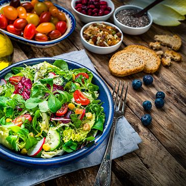 Fresh mixed salad with various vegetables and healthy toppings on rustic wooden table.