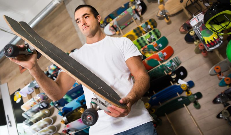 Portrait of nice man choosing new skateboard at shop