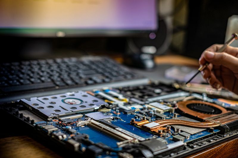 Hand technician repairing broken laptop notebook computer with a screwdriver