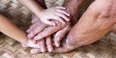 Young and old hands joined together on a woven mat.