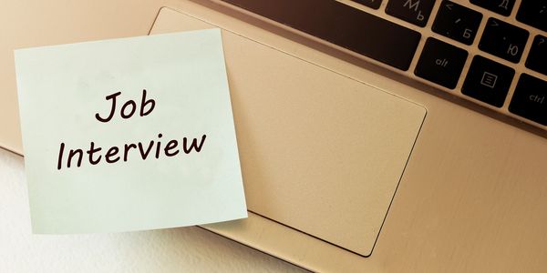 Sticky note with 'Job Interview' on laptop keyboard.