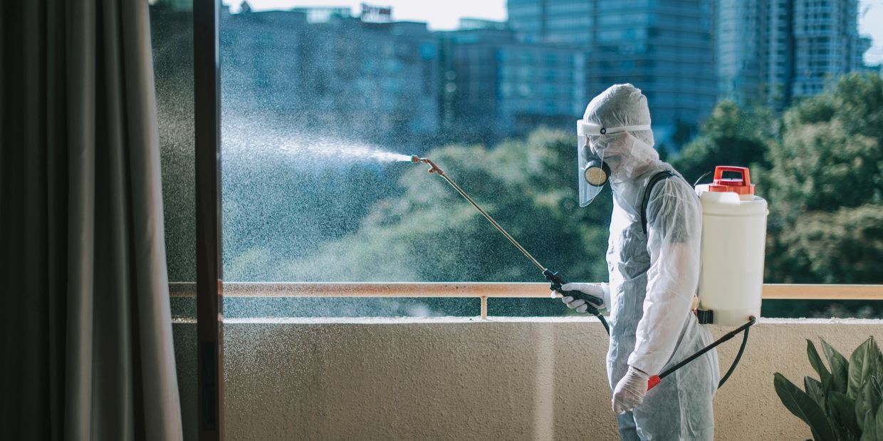 Person in hazmat suit disinfecting a balcony.