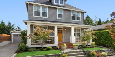 A charming two-story house with a front porch and garden.