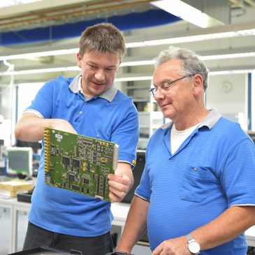 Two engineers inspecting a circuit board in a lab.