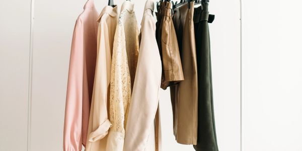 Neutral-toned clothing neatly hung on a rack against a white background.